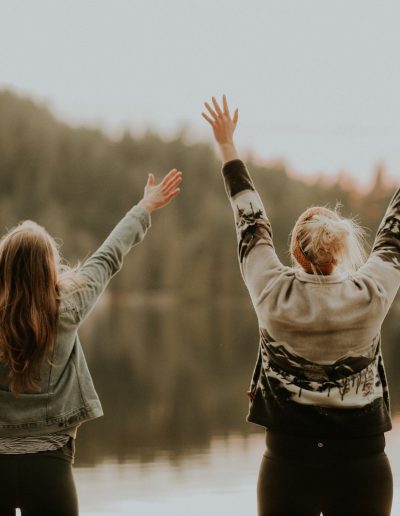 dvi moterys aukštyn rankos stovi prie vandens telkinio